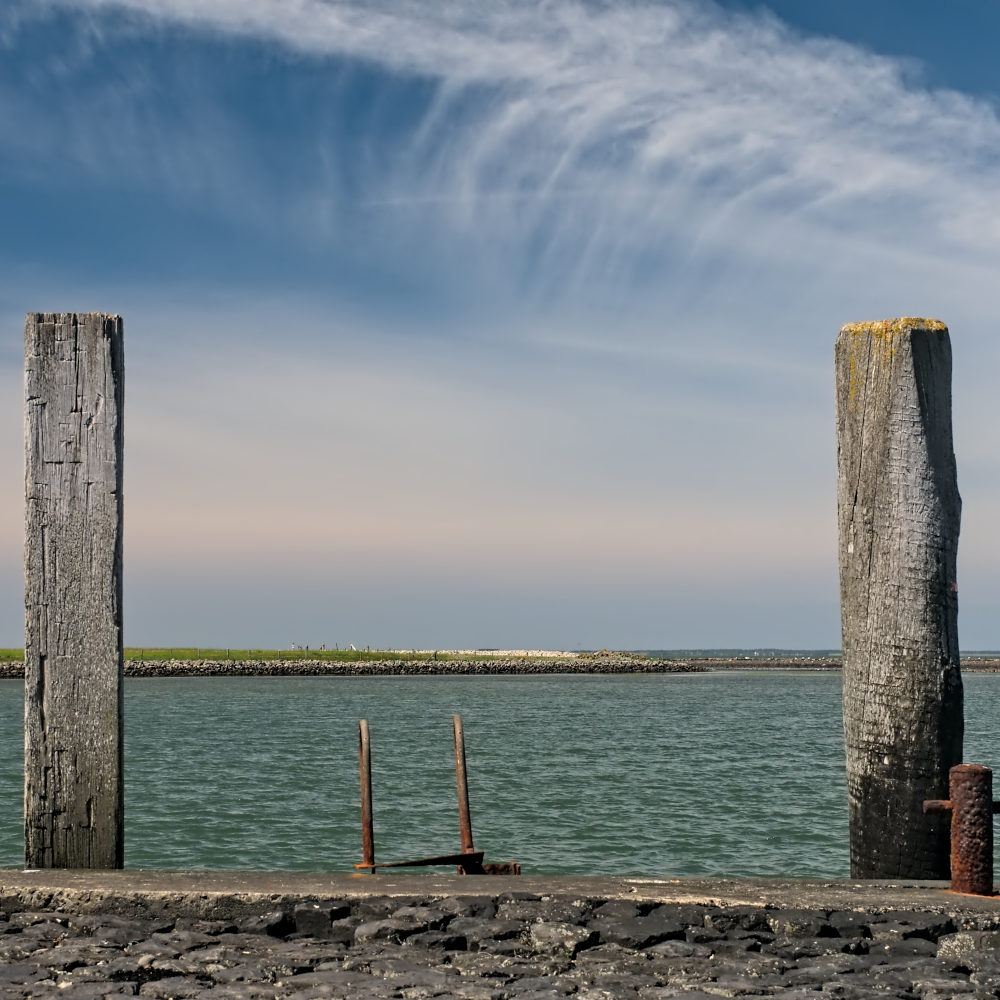 Hafenmole mit Anlegepfählen und Blick aufs Meer